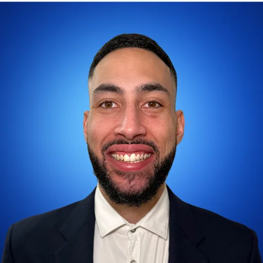 Malik Wilson smiling, wearing a dark blazer and white shirt